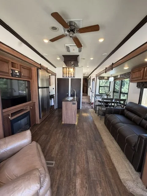 Long open living space with ceiling fan, fireplace and dining area