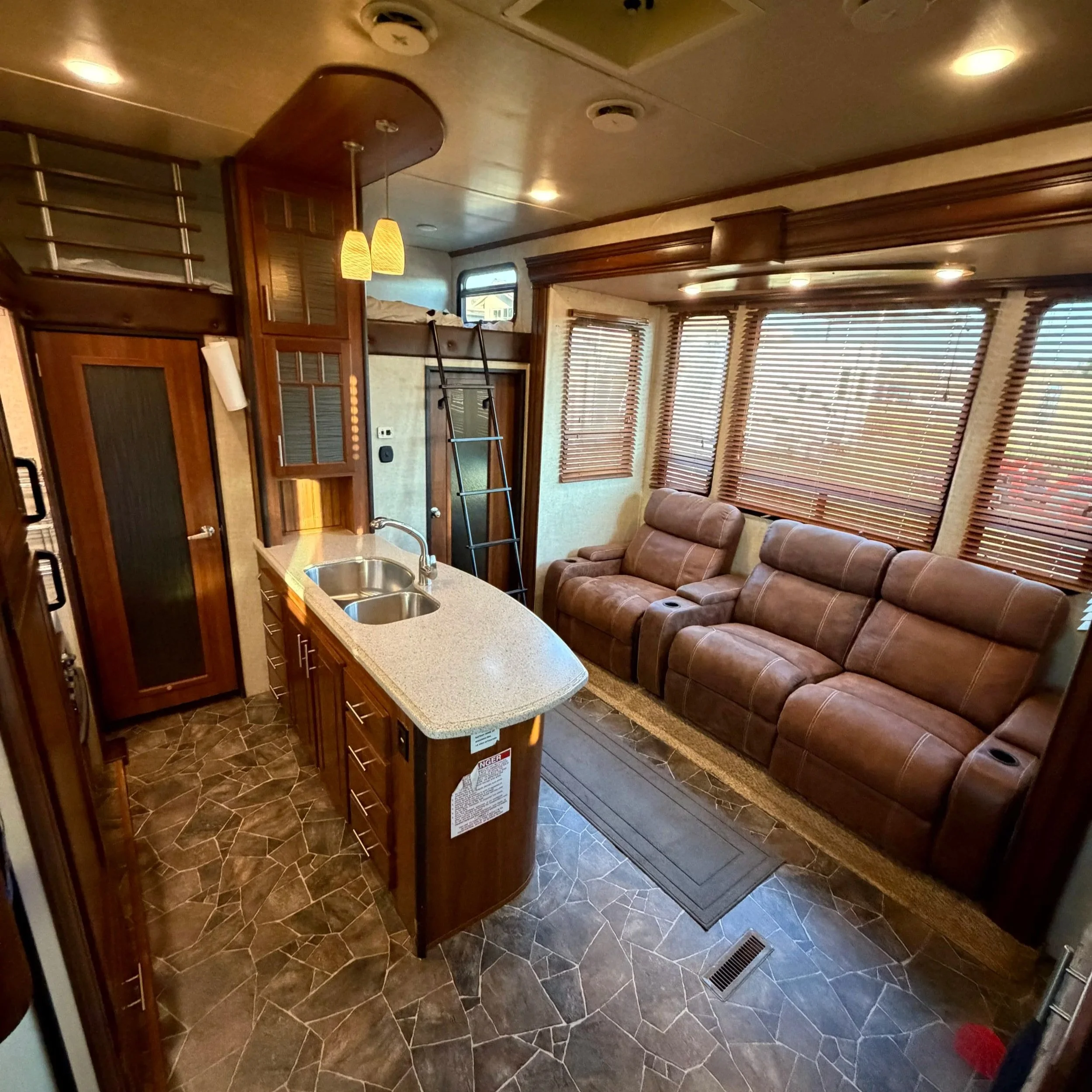 Trailer living room with leather theater recliners, kitchen island and loft bunk